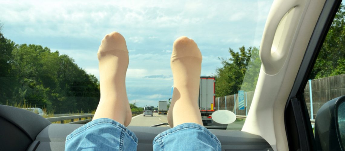 Legs in compression stockings rest on the car's torpedo. Concept for prevention of varicose veins and deep vein thrombosis during long journeys.