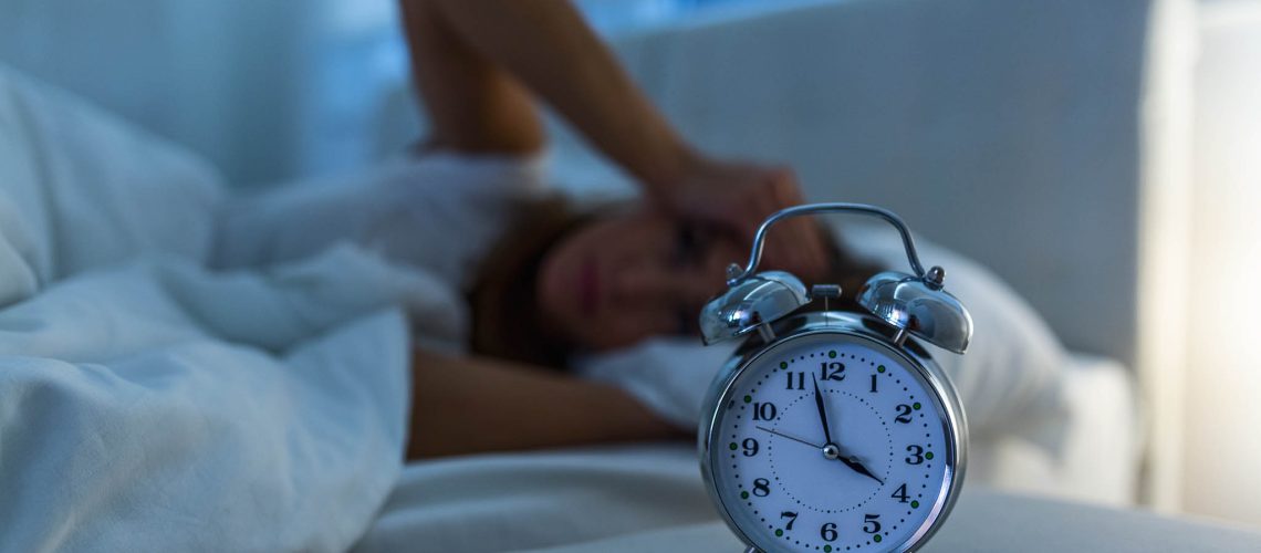 young beautiful woman at home bedroom lying in bed late at night trying to sleep suffering insomnia sleeping disorder or scared on nightmares looking sad worried and stressed