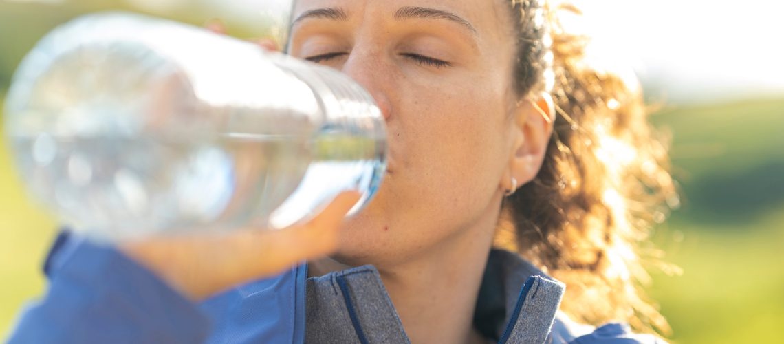 Mulher se hidratando e cuidando do hipotireoidismo no verão