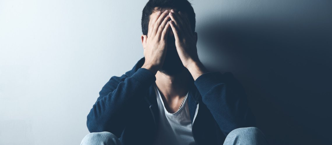 sad man sitting on ground on dark background