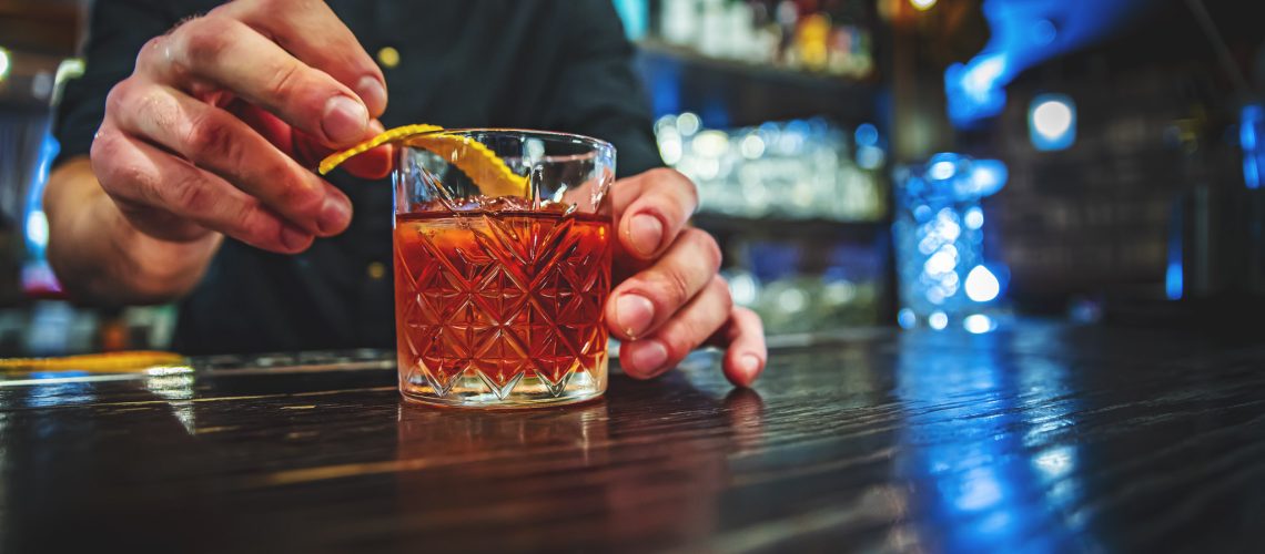 man hand bartender making negroni cocktail in bar