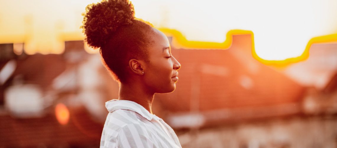 Young African American woman is on the balcony at sunset