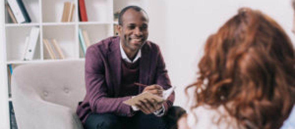 Smiling african american psychiatrist talking to young couple