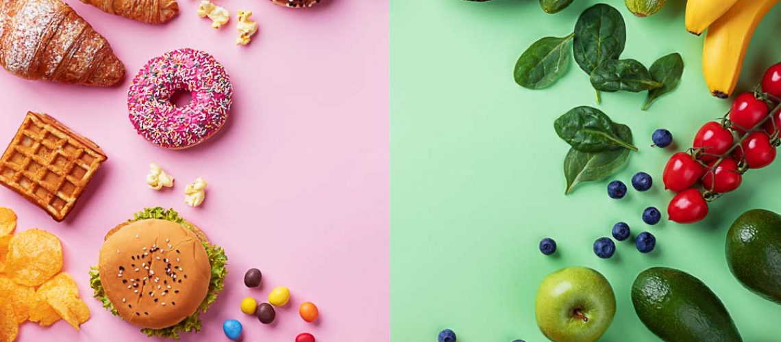 Healthy and unhealthy food background from fruits and vegetables vs fast food, sweets and pastry top view. Diet and detox against calorie and overweight lifestyle concept.
