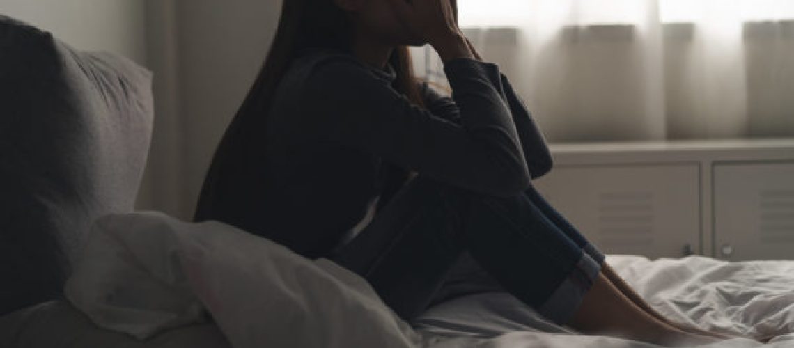 Suffer from depression , mental health problem. asian young woman sitting on the bed feeling depressed.