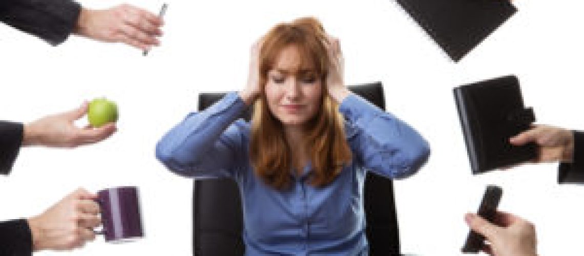overwhelmed business woman sitting at her desk surrounded by many male hands holding different objects