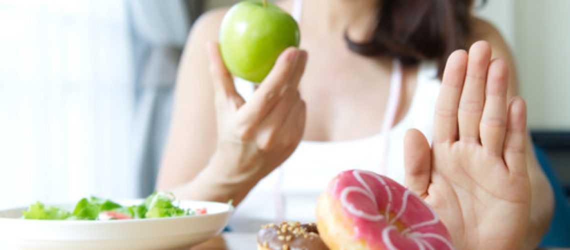 Woman rejecting junk food or unhealthy food such as donuts and c