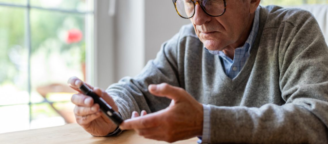 Mature Man Checking Blood Sugar Level With Glucometer